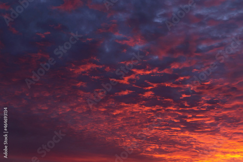 Epic dramatic sunrise, sunset orange red pink clouds in sunlight on blue sky background texture