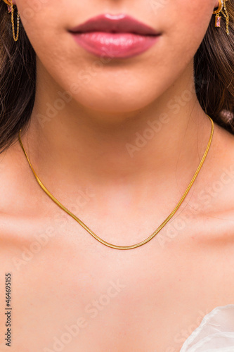 Beautiful young woman wearing a golden snake chain necklace and golden earings