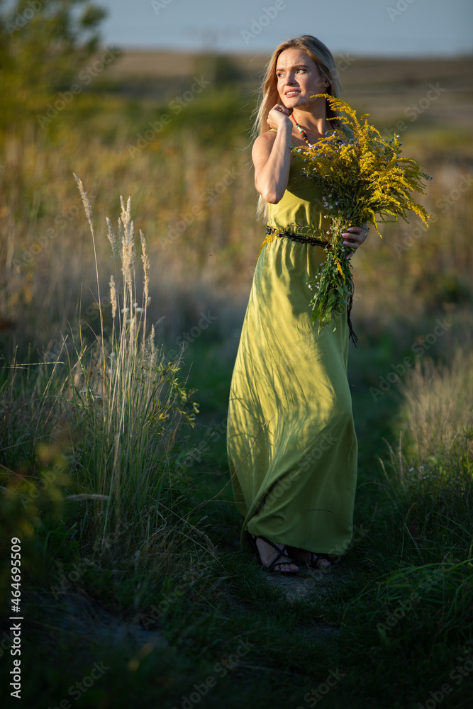 Obraz premium A young herbalist in love with a bouquet of herbs strolls romantically through the meadows.