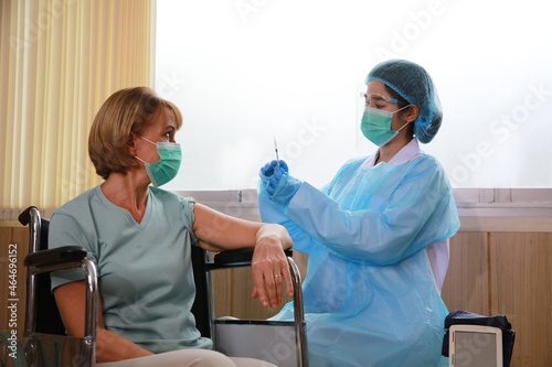 Portrait female elder wearing face maske sitting on wheel chair getting vaccination, corronavirus concpet photo