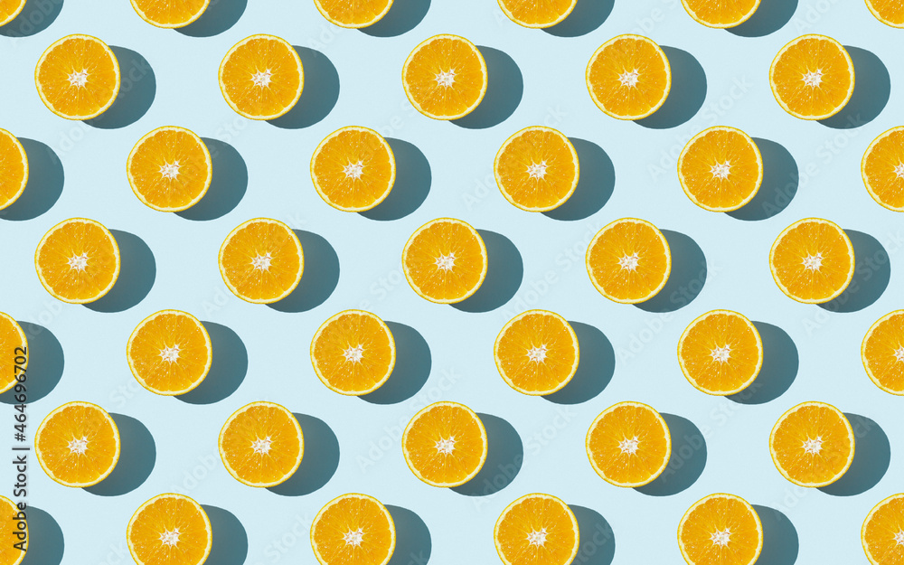 Seamless fruit pattern of fresh orange slices on blue background. Top view. Copy Space. Pop art design, creative summer concept. Half of citrus in minimal flat lay style.