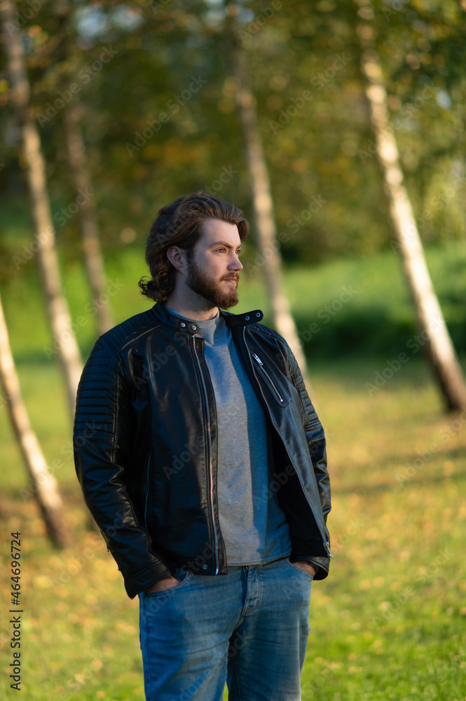 Young bearded man standing and looking at distance against a background of colorful autumn trees Young bearded man standing and looking at distance against a background of colorful autumn trees