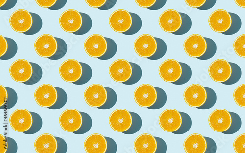 Fototapeta Naklejka Na Ścianę i Meble -  Seamless fruit pattern of fresh orange slices on blue background. Top view. Copy Space. Pop art design, creative summer concept. Half of citrus in minimal flat lay style.