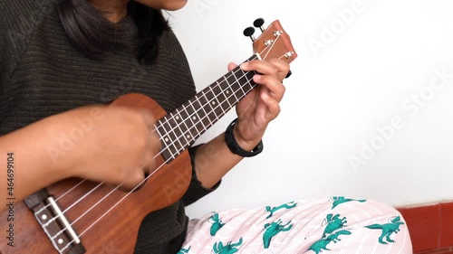 Young woman playing ukulele, close up, cropped.