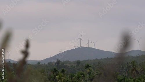 Wind turbine farm power generator on a mountain landscape with areca plantations in the foreground. Renewable, green energy resources for sustainable development
