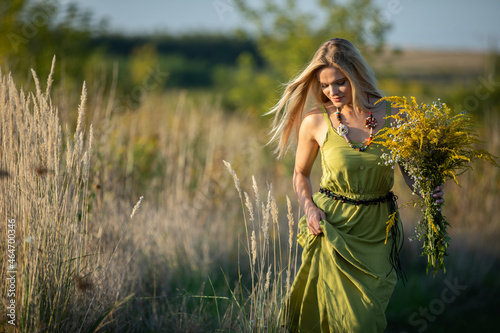 A young herbalist, full of love, walks, cradling her harvested herbs. Common goldenrod and winterflower. photo