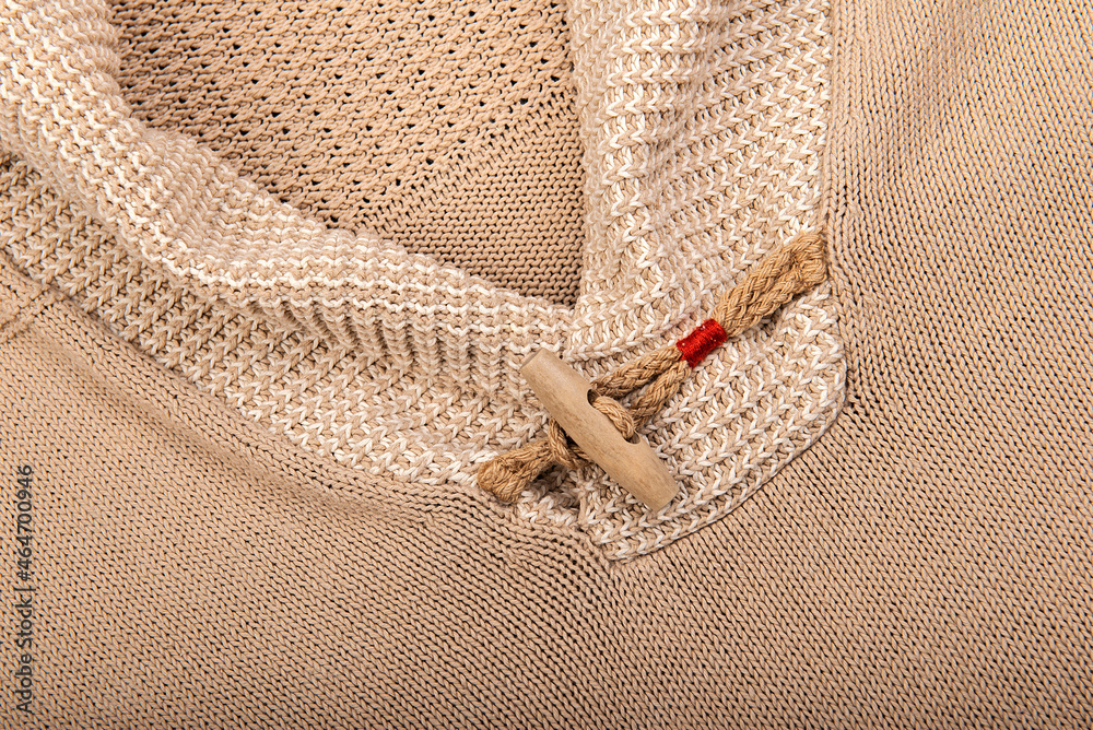 Close-up of knitted sweater collar with wooden button in pastel brown color tones Close-up of knitted sweater collar with wooden button in pastel brown color tones