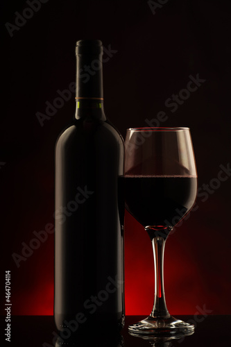 a red wine bottle with the glass half full
