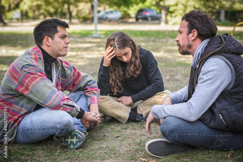 Three friends sit together in park and talk about problems © guruXOX