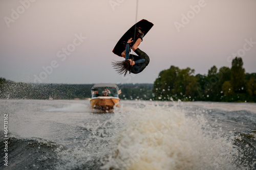 energy athletic male wakeboarder makes dangerous stunts on wakeboard