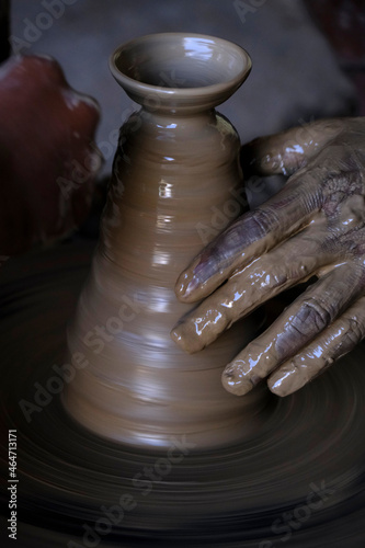  A potter prepares clay Pots or diya on potter's wheel in his residence ahead of Diwali festival. Wet and muddy hands of a craftsman shaping a clay vase on a pottery wheel.