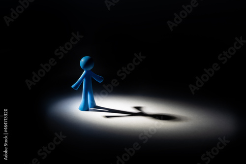 The figurine of a symbolic person stands in a circle of light and casts a long shadow