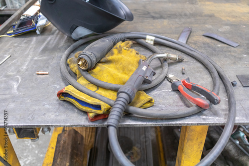 A gas welding torch, a welder's mask and gloves lie on a metal workbench in a locksmith's shop.