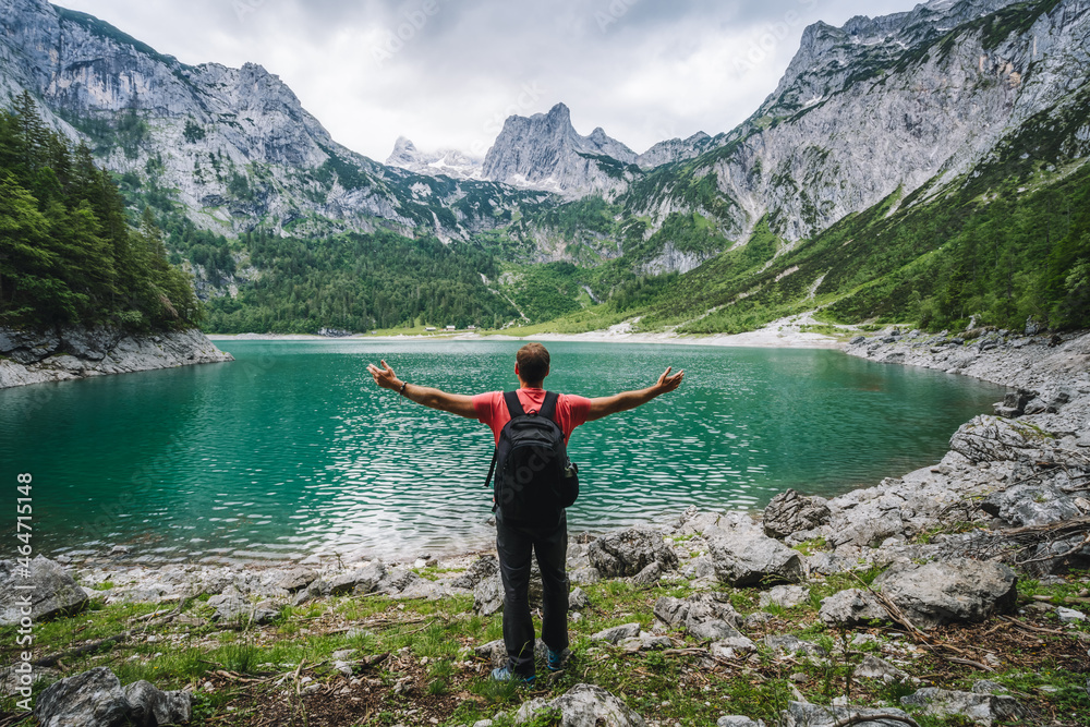 Happy traveler standing and admiring Dachstein peak mountains on a Upper Gosau Lake. Gosau, Salzkammergut, Austria, Europe