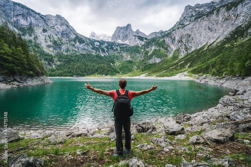 Happy traveler standing and admiring Dachstein peak mountains on a Upper Gosau Lake. Gosau, Salzkammergut, Austria, Europe