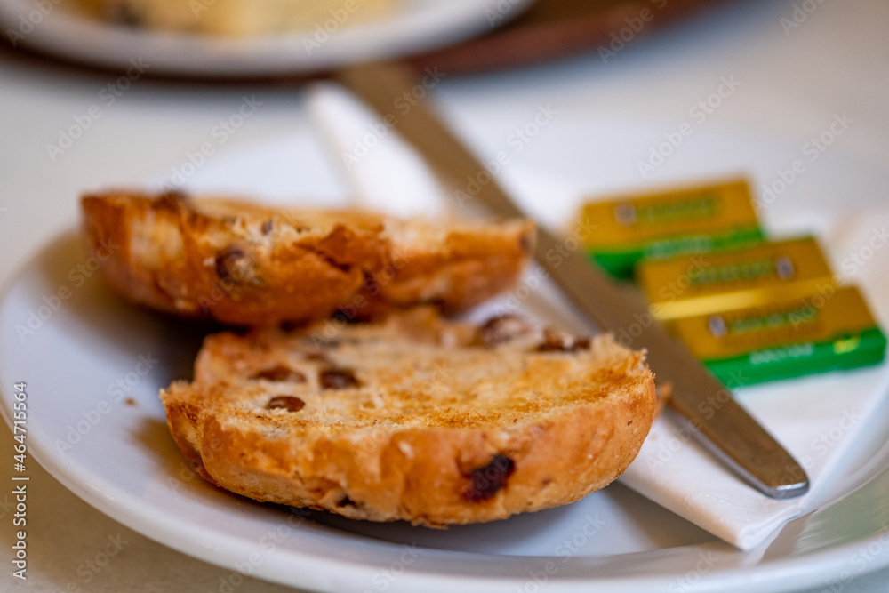 Traditional toasted tea cake and butter on a white plate with selective intentional close focus Traditional toasted tea cake and butter on a white plate with selective intentional close focus