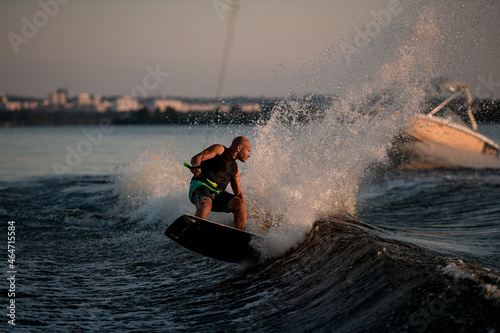 active athletic man trying to stand on splashing wave on a wakeboard