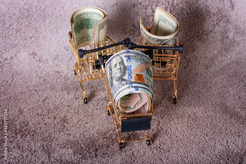 Three shopping baskets with dollars in them on a gray background. Financial concept.