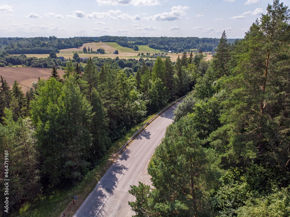 Areal drone photography of highway near forest and agriculture fields.