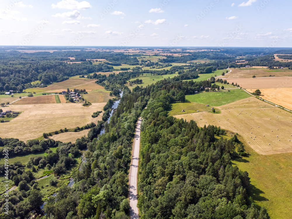 Countryside high way road through forest and near small river from drone view.