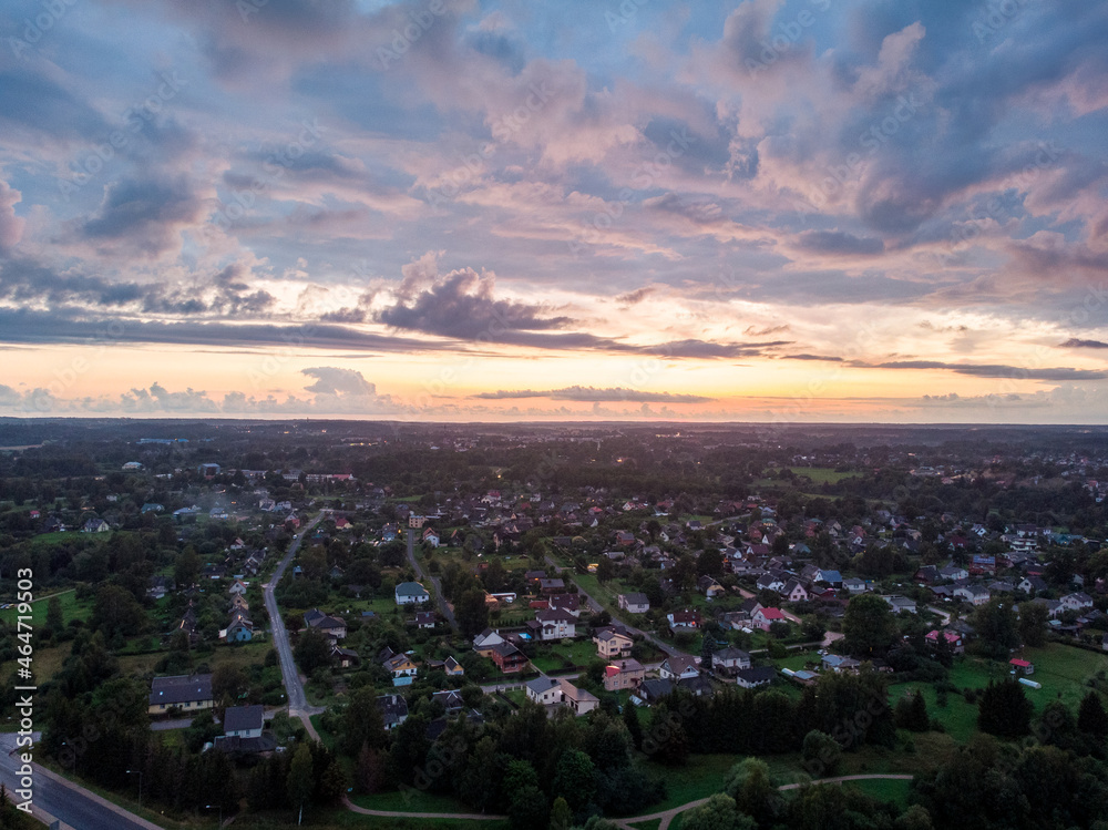 Late evening areal drone suburbs sunset view with small many private houses.