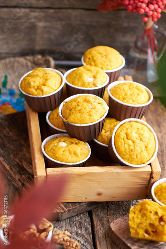 Pumpkin muffins with white chocolate and walnuts. Side view, wooden background.