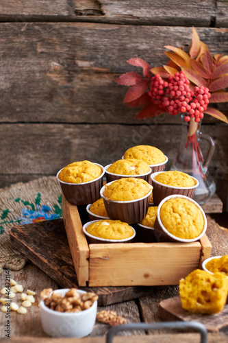 Pumpkin muffins with white chocolate and walnuts. Side view, wooden background. Red rowan