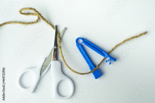 sterile scissors and umbilical cord clamp with a rope on white background. Birth at home, cutting umbilical cord concept. photo