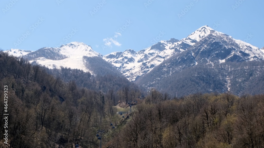 picturesque landscape of snow-capped mountains with white clouds on a blue sky on a sunny day at Krasnaya Polyana in Sochi, Russia