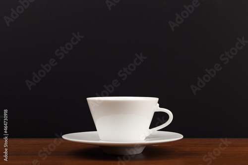 Selective focus, close up of white ceramic coffee or tea cup against dark black background with copy space