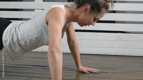 Fitness young girl doing push ups at home.