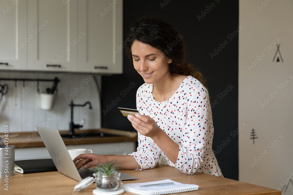 Happy shopaholic using laptop for online shopping, using credit card for payment, spending money on internet. Customer making transactions on bank application, getting good cashback for purchase