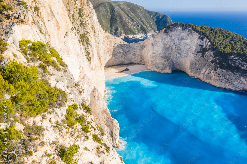 Aerial view of beautiful Navagio or Shipwreck beach on Zakynthos Island, Greece. Tourists on cliff edge enjoy view on summer travel trip