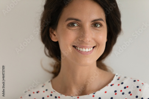 Close up studio portrait of happy beautiful Latin 30s woman with fine face skin looking at camera with toothy smile. Young mid adult female model isolated on white. Dental care, cosmetology concept