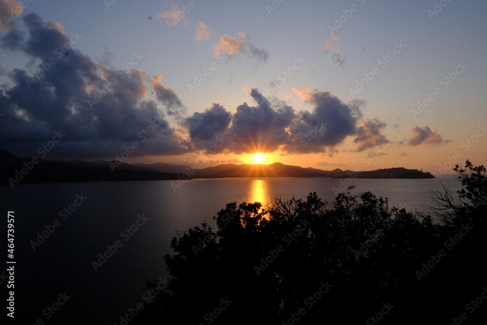 tramonto sul mare su un'isola, sole tra le nuvole