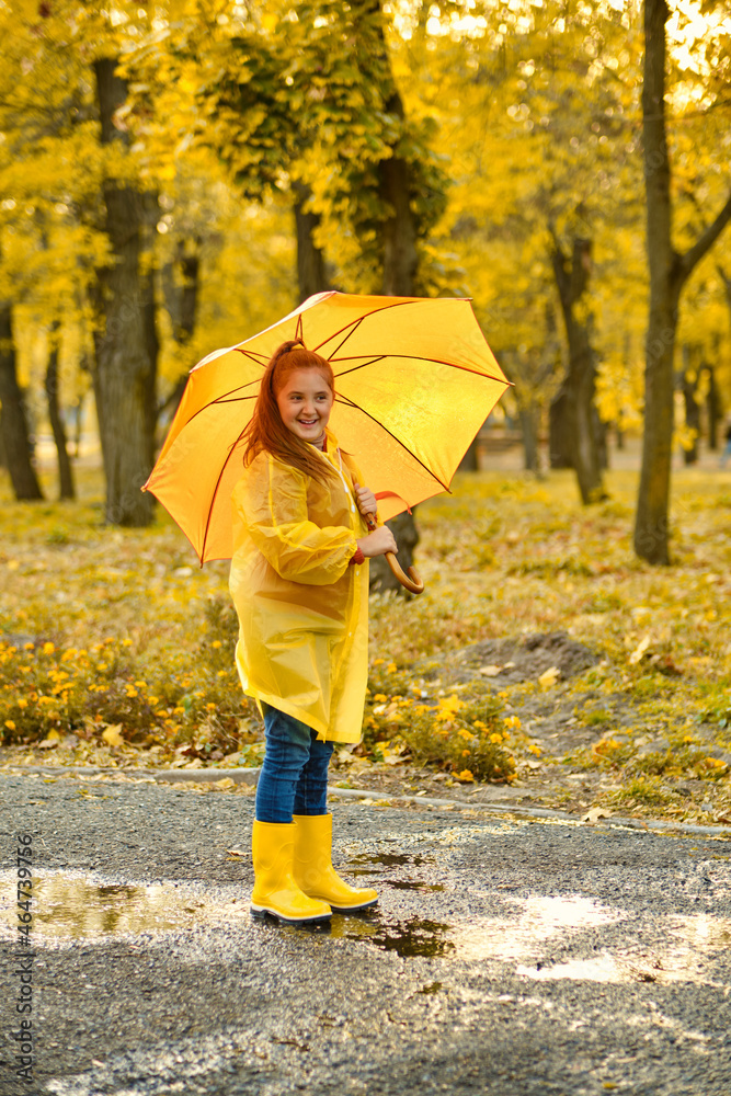 Obraz premium happy child girl with an umbrella and rubber boots