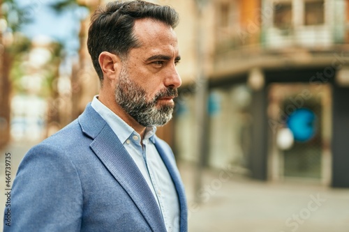 Middle age businessman with relaxed expression standing at the city.