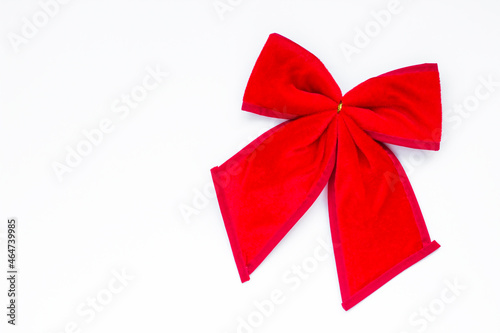 Christmas bow made of red fabric on white surface with copy space