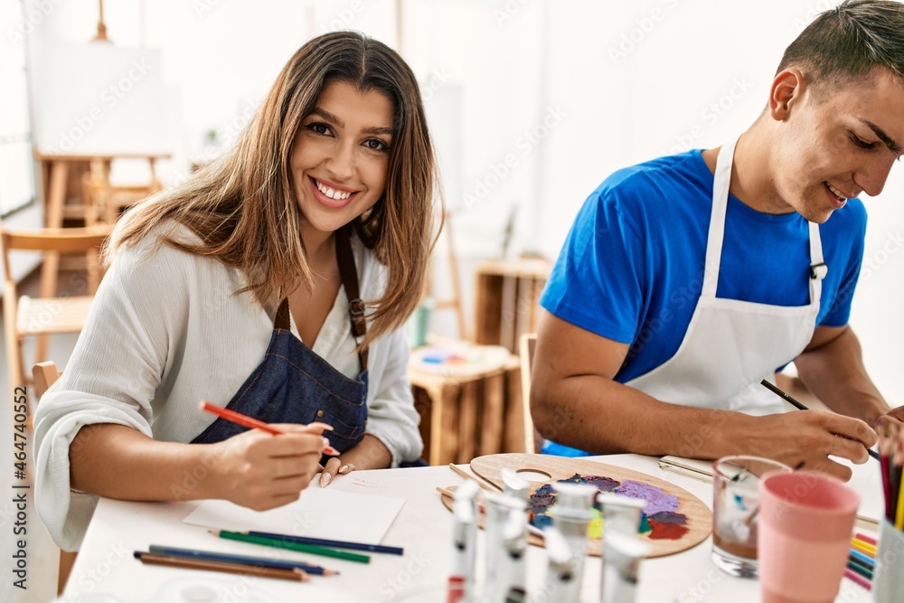 Two students smiling happy painting sitting on the table at art school. Two students smiling happy painting sitting on the table at art school.