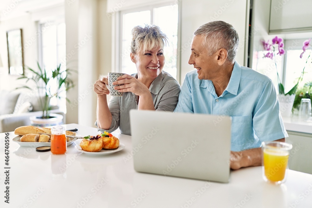 Senior caucasian couple having breakfast using laptop at the kitchen. Senior caucasian couple having breakfast using laptop at the kitchen.