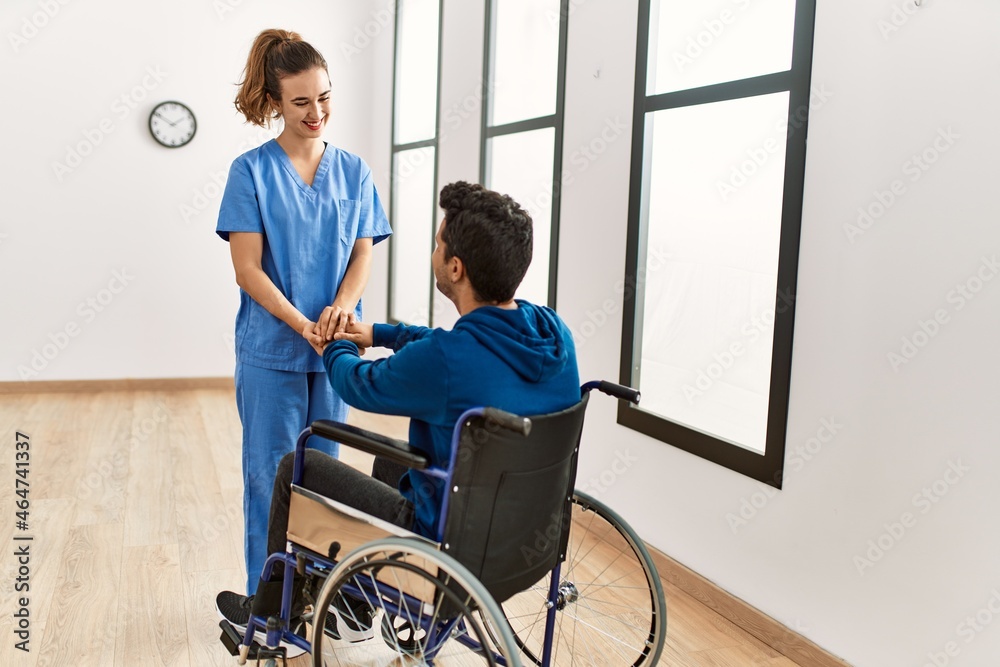 Young disabled man and physiotherapist smiling happy shaking hands at the clinic. Young disabled man and physiotherapist smiling happy shaking hands at the clinic.