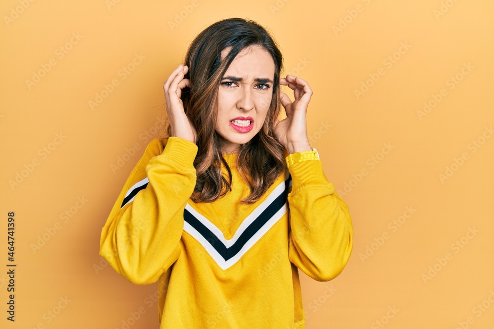 Young hispanic girl wearing casual clothes covering ears with fingers with annoyed expression for the noise of loud music. deaf concept. Young hispanic girl wearing casual clothes covering ears with fingers with annoyed expression for the noise of loud music. deaf concept.