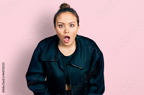 Young hispanic girl wearing sportswear afraid and shocked with surprise and amazed expression, fear and excited face.