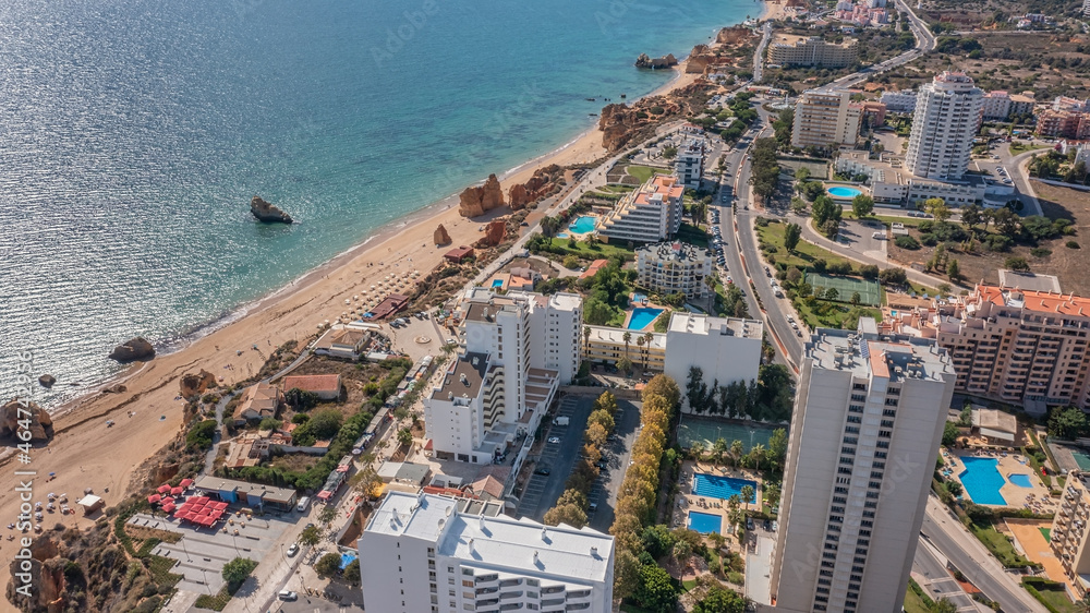 Obraz premium Aerial view of the city of Portimao over residential buildings, high-rise buildings, on the beach Praia de Rocha with tourists.