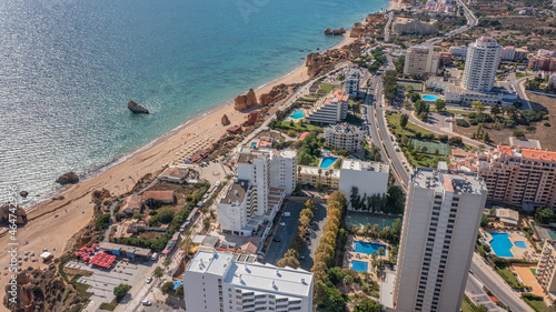 Aerial view of the city of Portimao over residential buildings, high-rise buildings, on the beach Praia de Rocha with tourists.