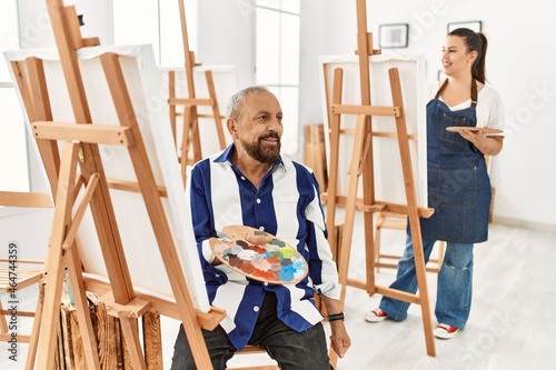 Senior artist man at art studio looking away to side with smile on face, natural expression. laughing confident.