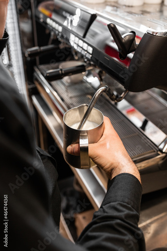 Barista heats milk with high-pressure steam for making lattes. Flowing fresh ground coffee. Drinking roasted black coffee in the morning.