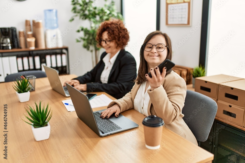 Group of two women working at the office. Mature woman and down syndrome girl working at inclusive teamwork. Group of two women working at the office. Mature woman and down syndrome girl working at inclusive teamwork.