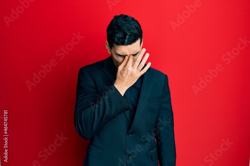 Handsome hispanic man wearing business clothes tired rubbing nose and eyes feeling fatigue and headache. stress and frustration concept.