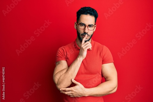 Young hispanic man wearing casual clothes and glasses asking to be quiet with finger on lips. silence and secret concept.